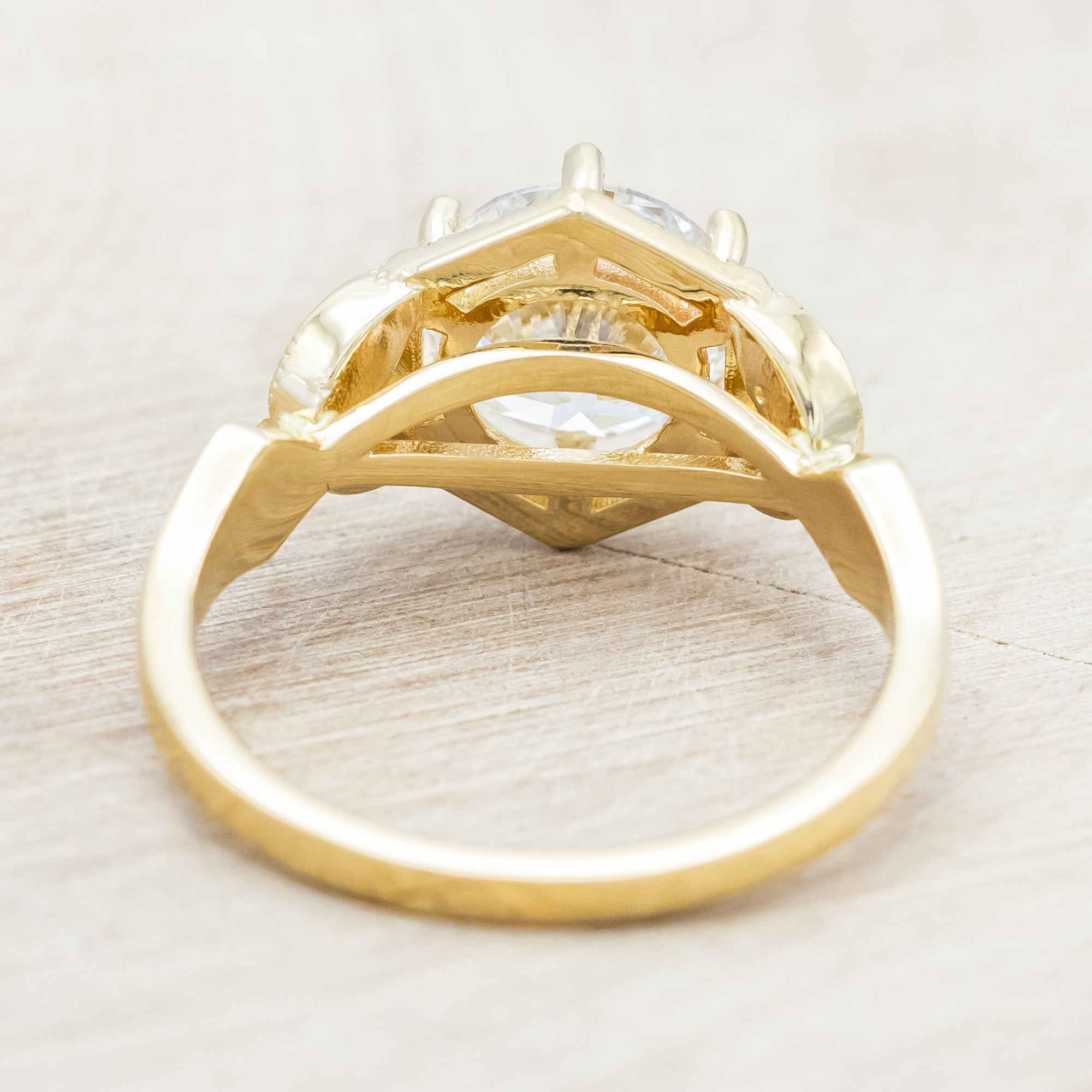 Yellow gold ring with a lab-grown diamond and diamond accents on a beige background