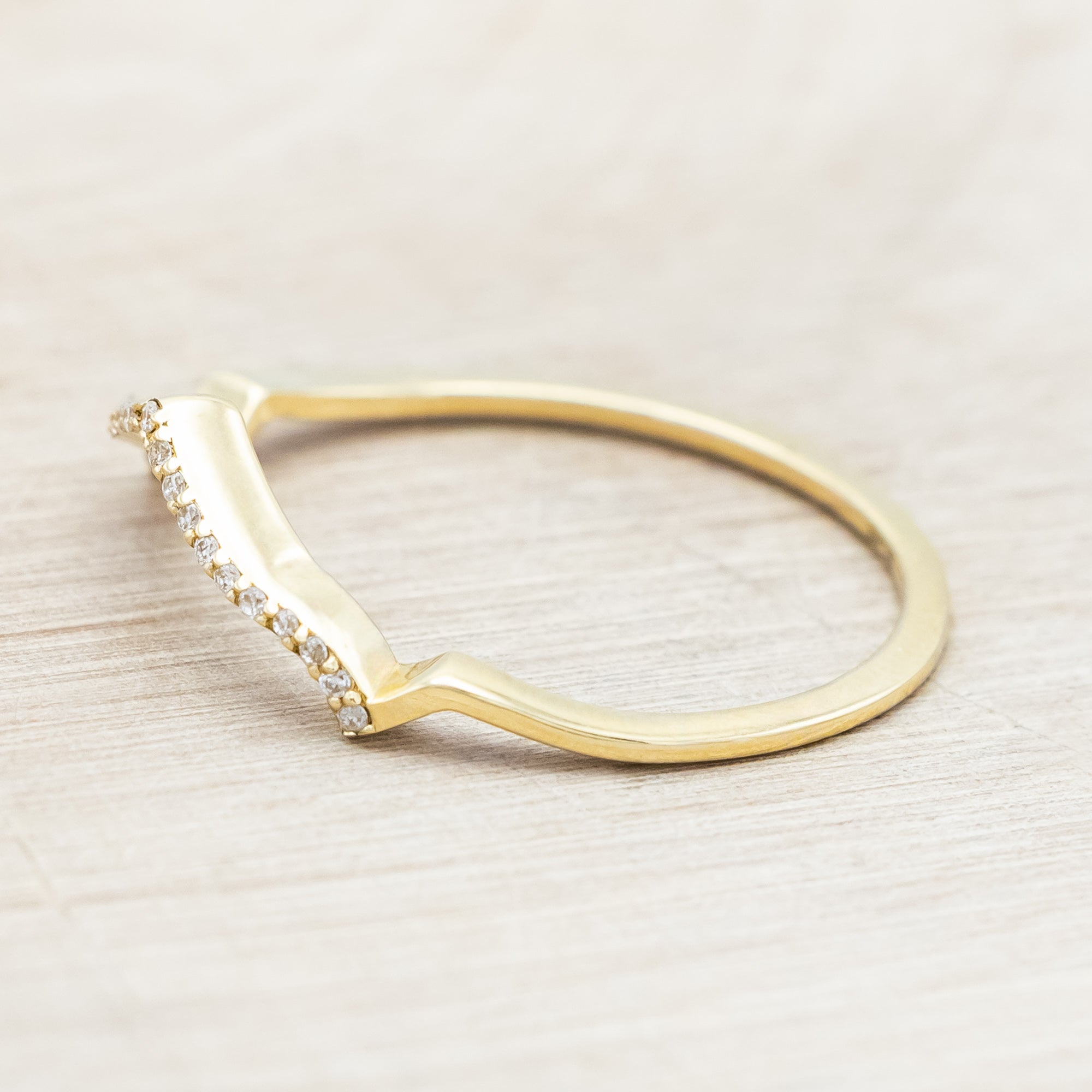 Yellow gold ring with diamond accents on a beige background
