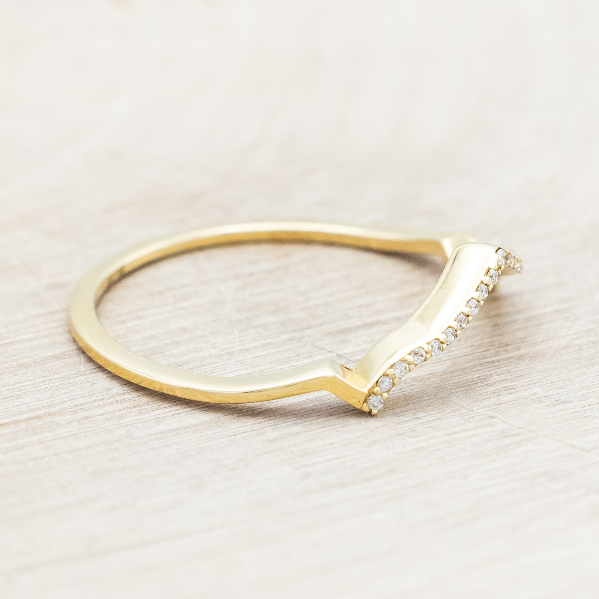 Yellow gold ring with diamond accents on a beige background