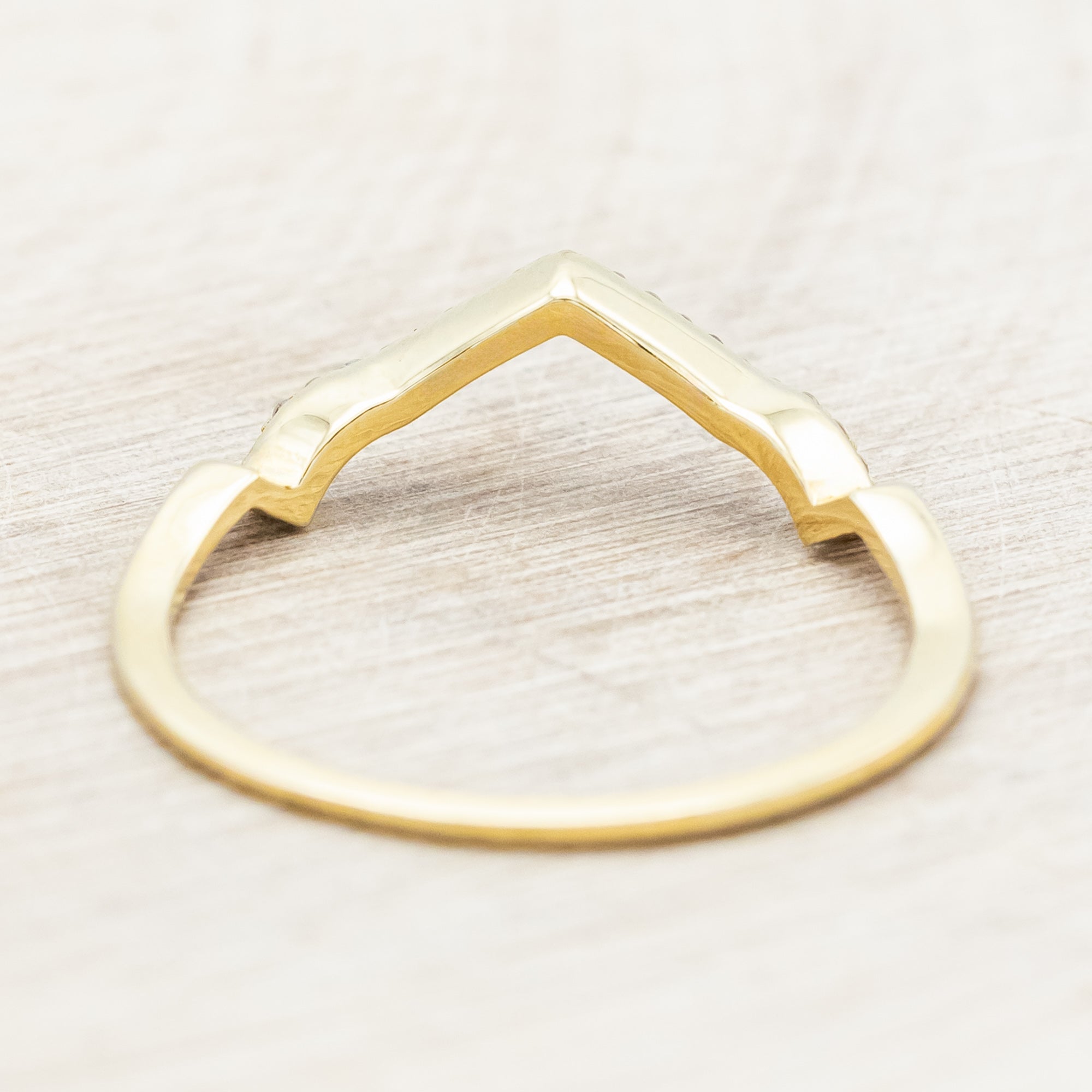 Yellow gold ring with diamond accents on a beige background