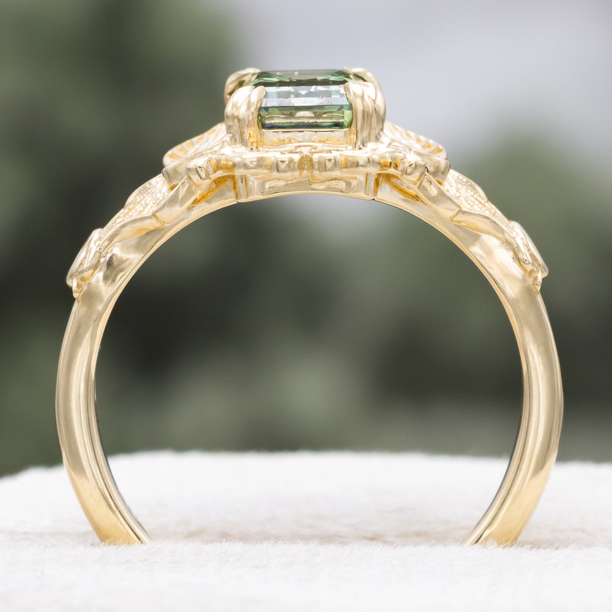 Gold ring with a green lab diamond, moth filigree, and diamond accents on a neutral background