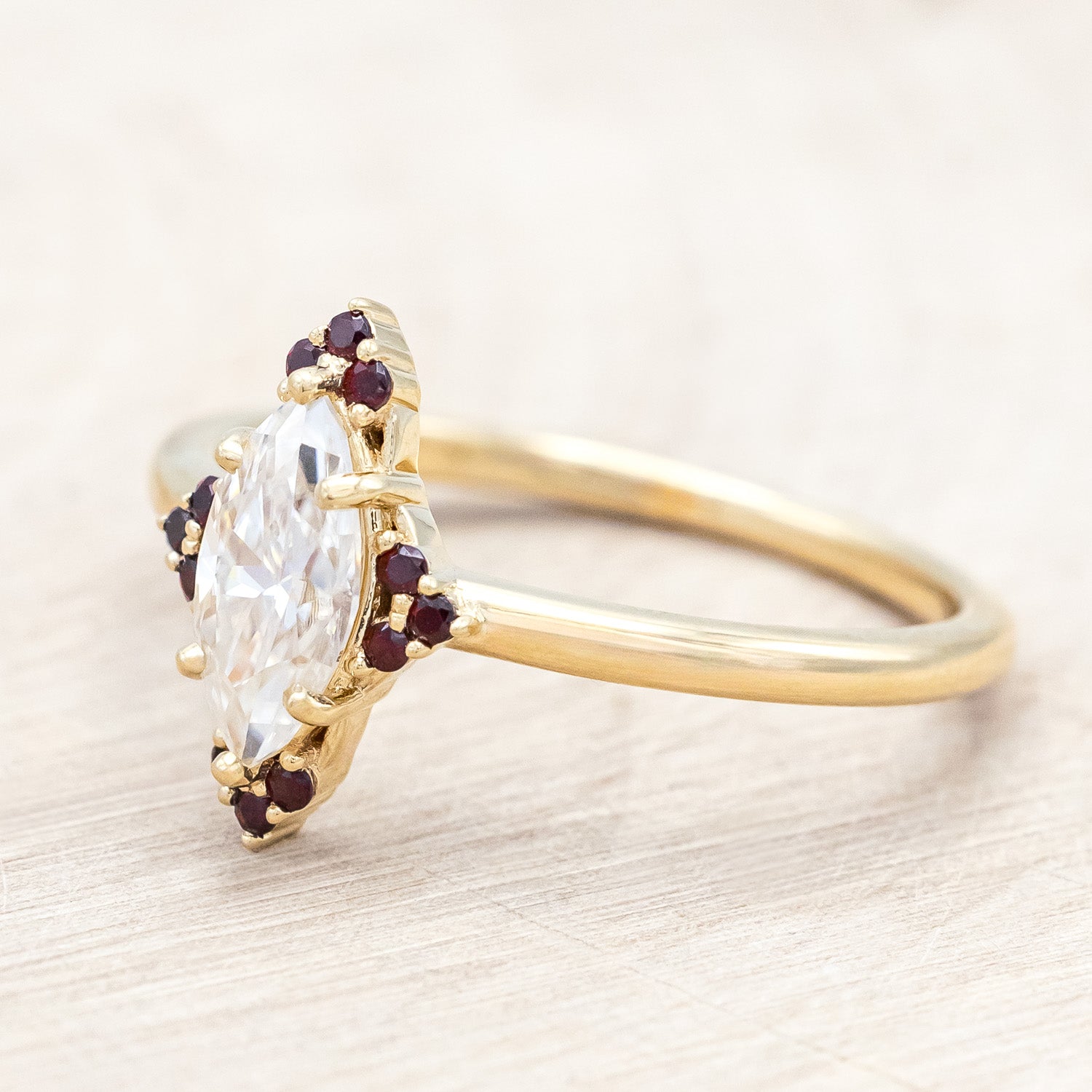 14K gold ring with Moissanite center stone and smaller red garnets on a light background