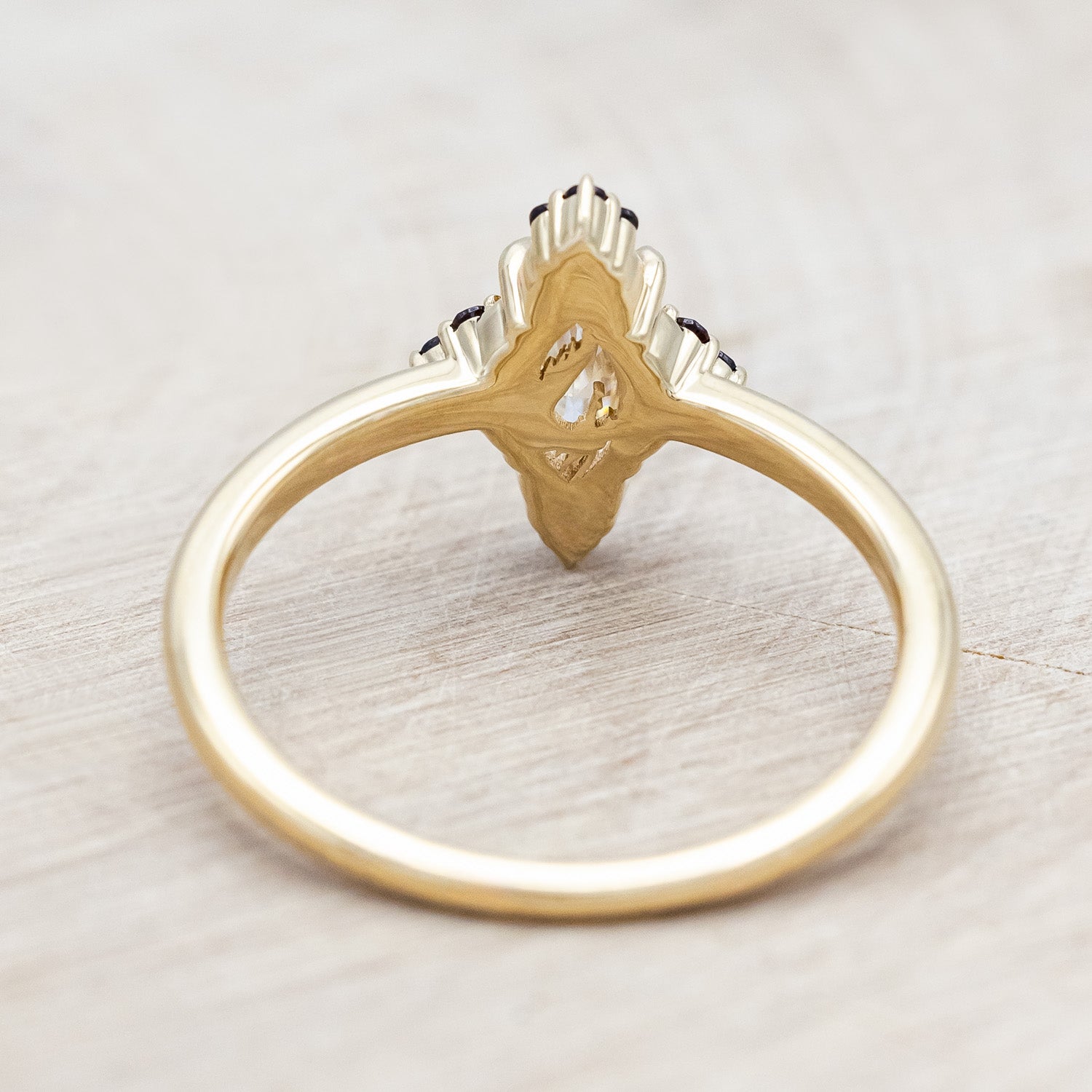 14K gold ring with Moissanite center stone and smaller red garnets on a light background