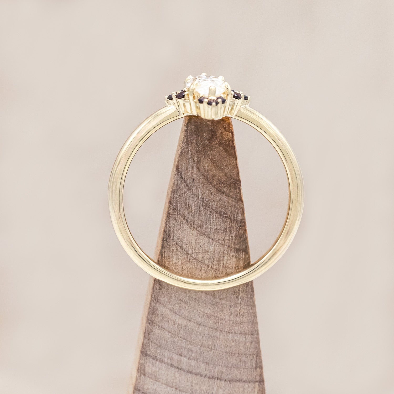 14K gold ring with Moissanite center stone and smaller red garnets on a light background