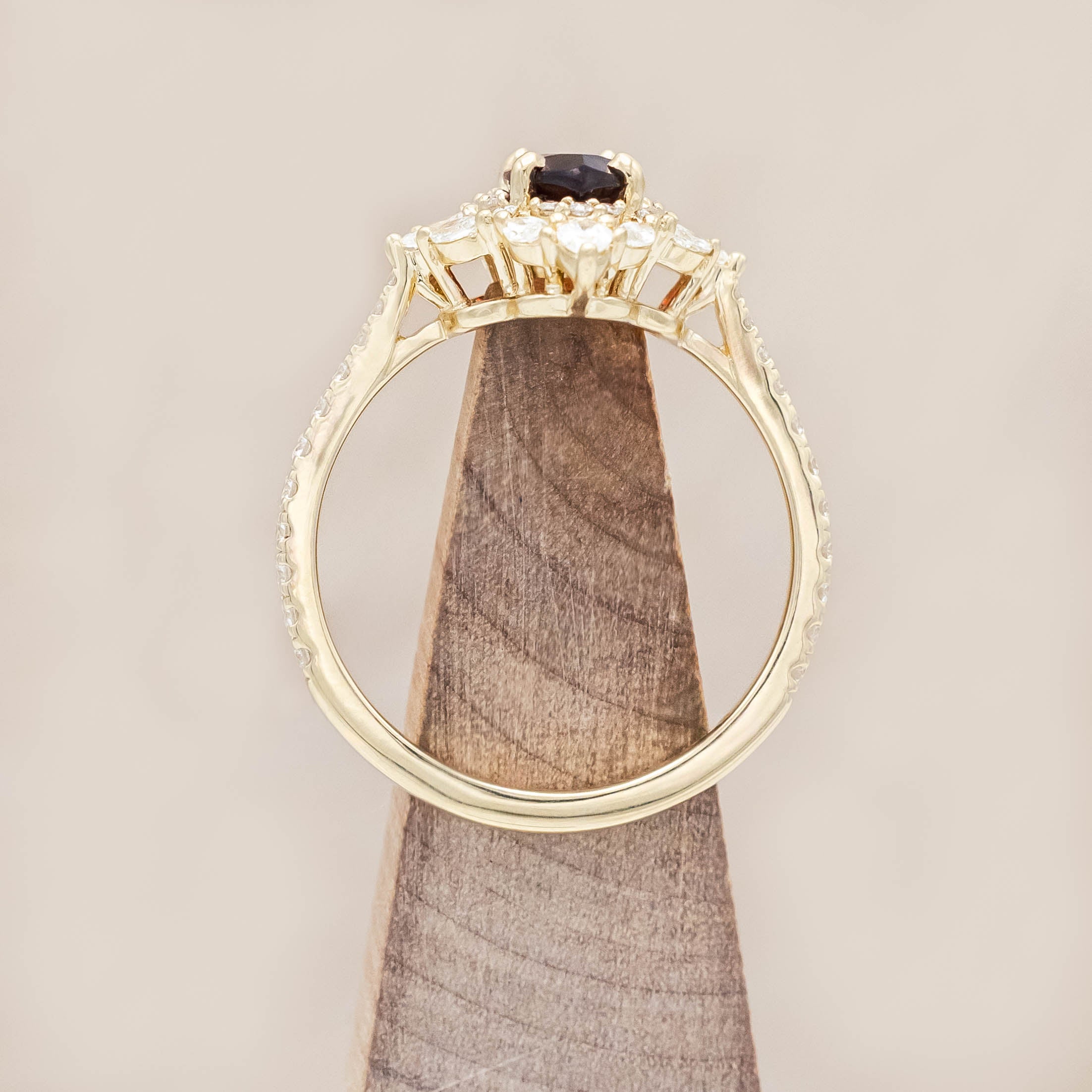 Gold ring with a red garnet and diamond accents on a light wooden background