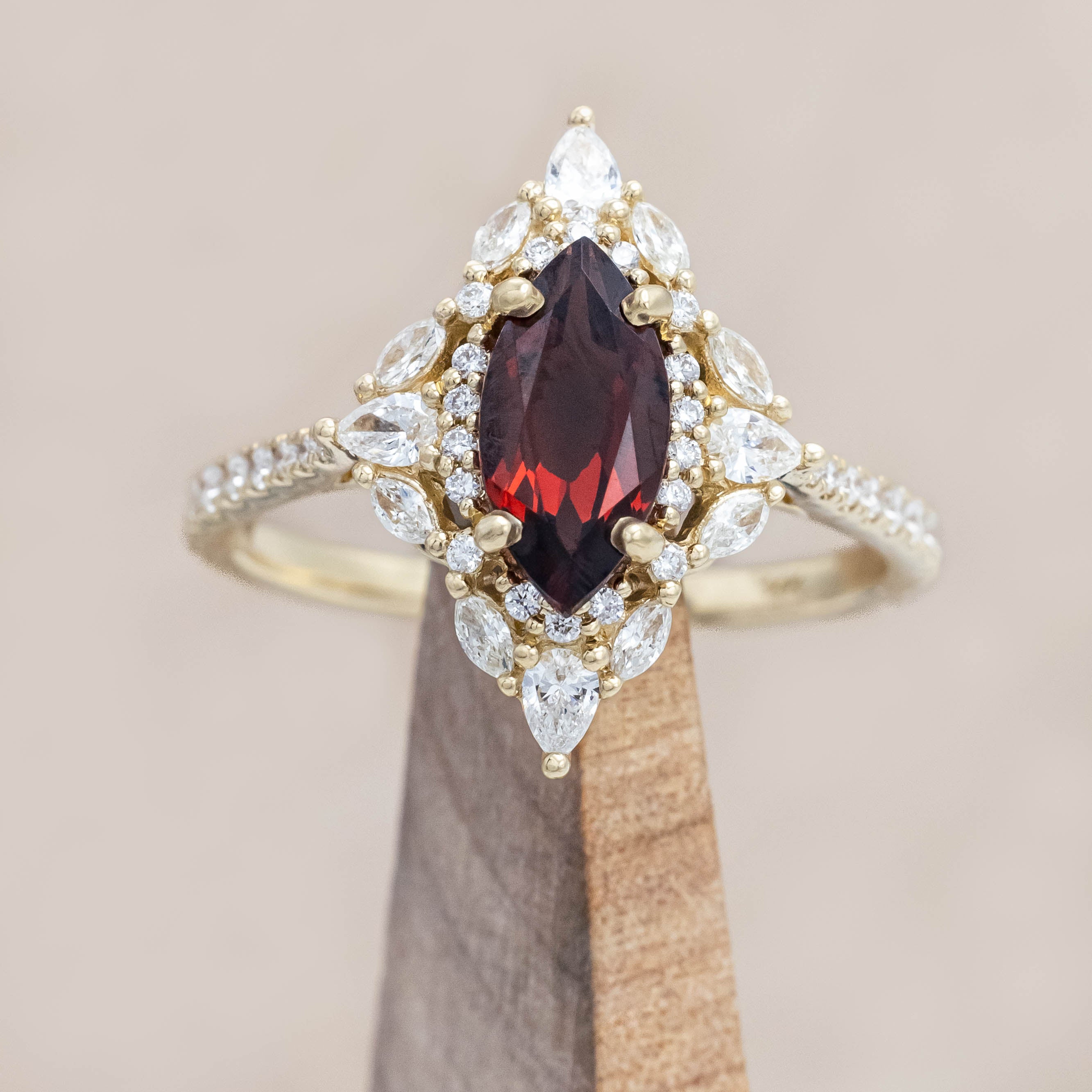 Gold ring with a red garnet and diamond accents on a neutral background