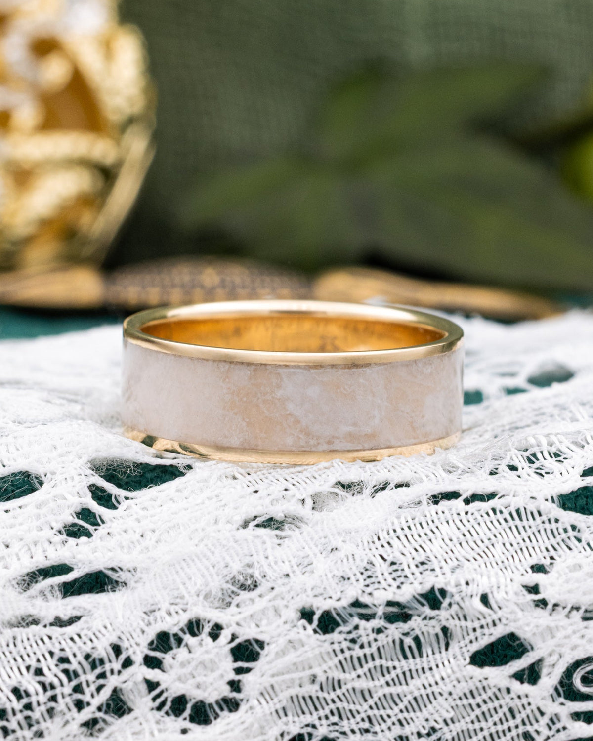 Yellow gold ring with a wedding dress inlay on a lace and decorative background