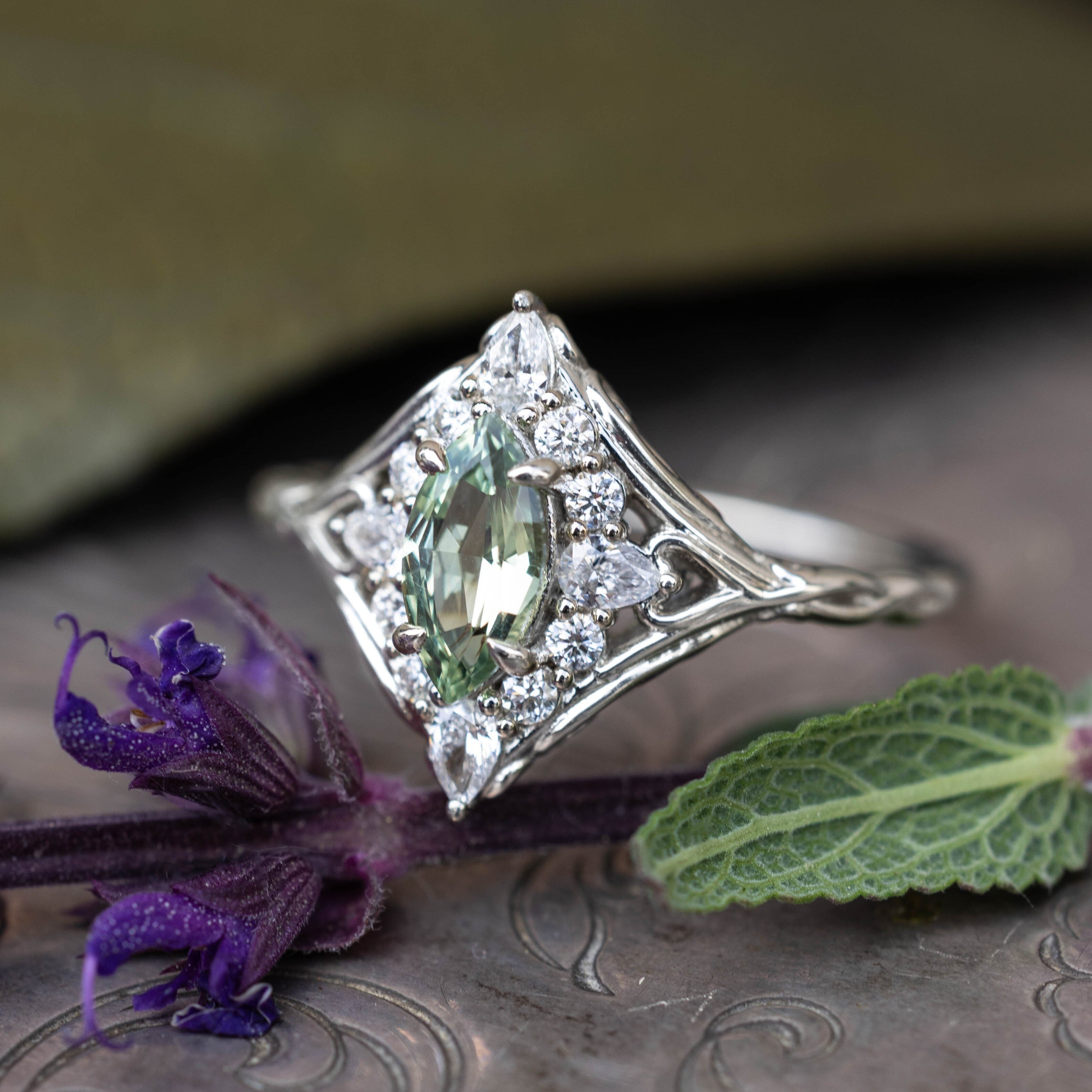White gold ring with sapphire center stone and diamond halo on a natural decorative background