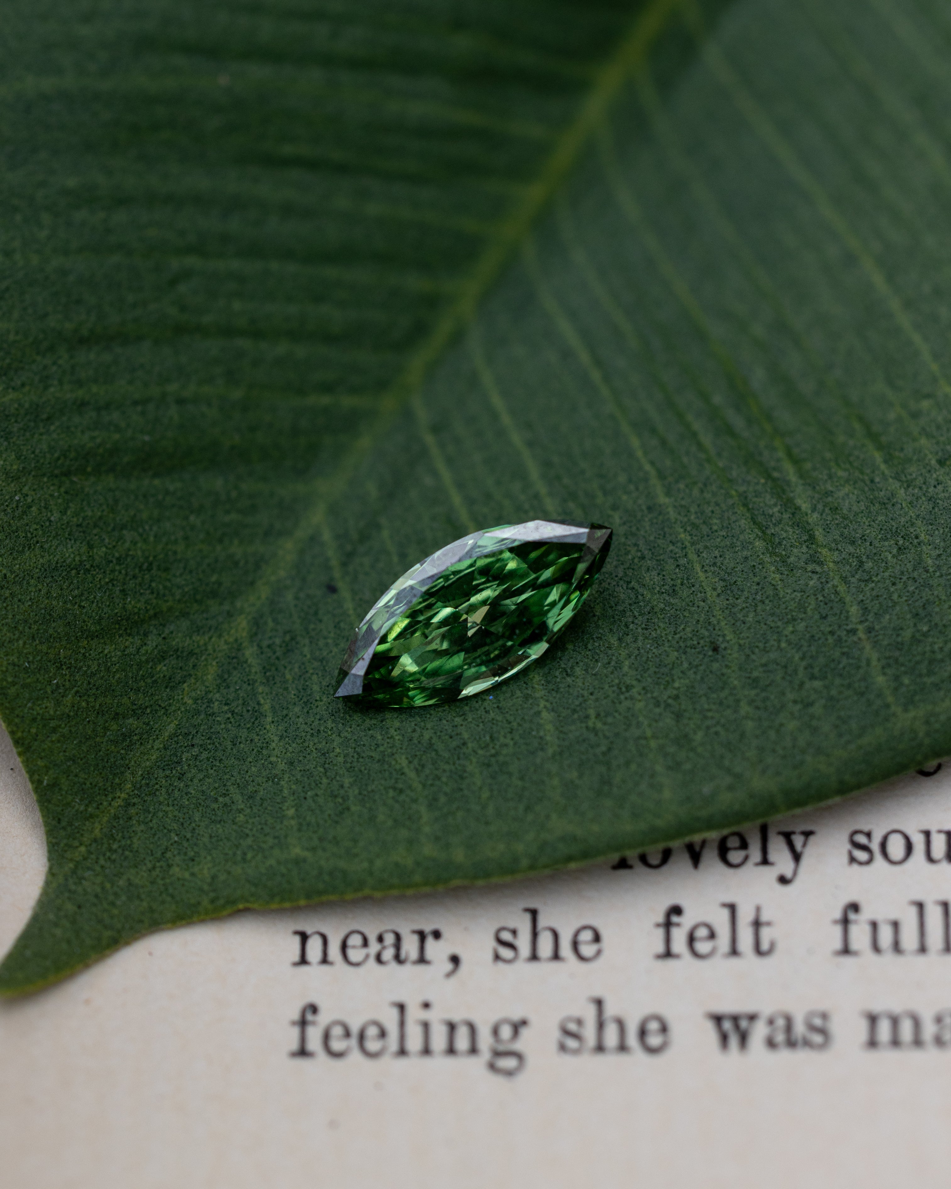 Green lab diamond sitting on top of a green leaf and piece of paper
