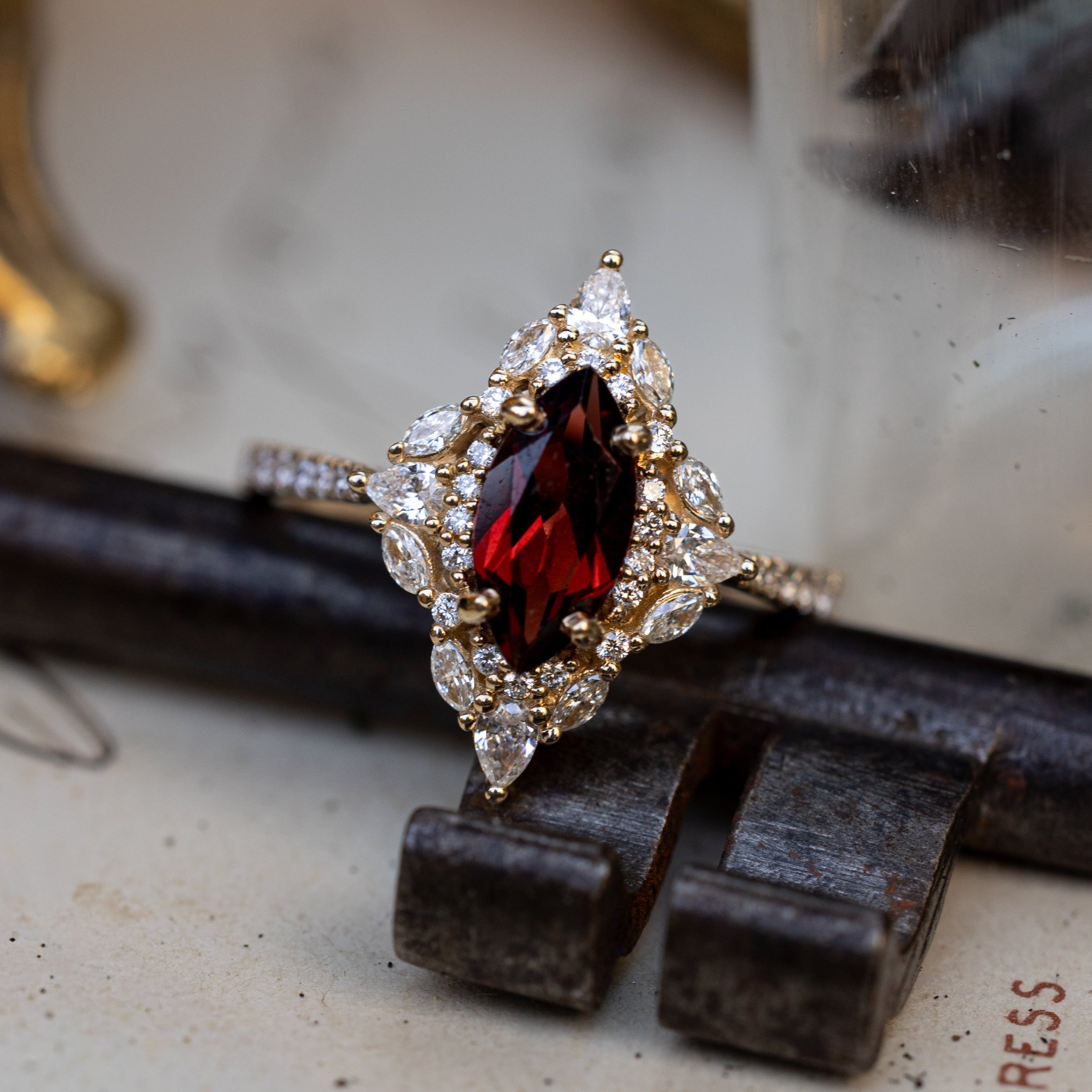 Gold ring with a garnet centerstone and diamond accents on an old key and paper background