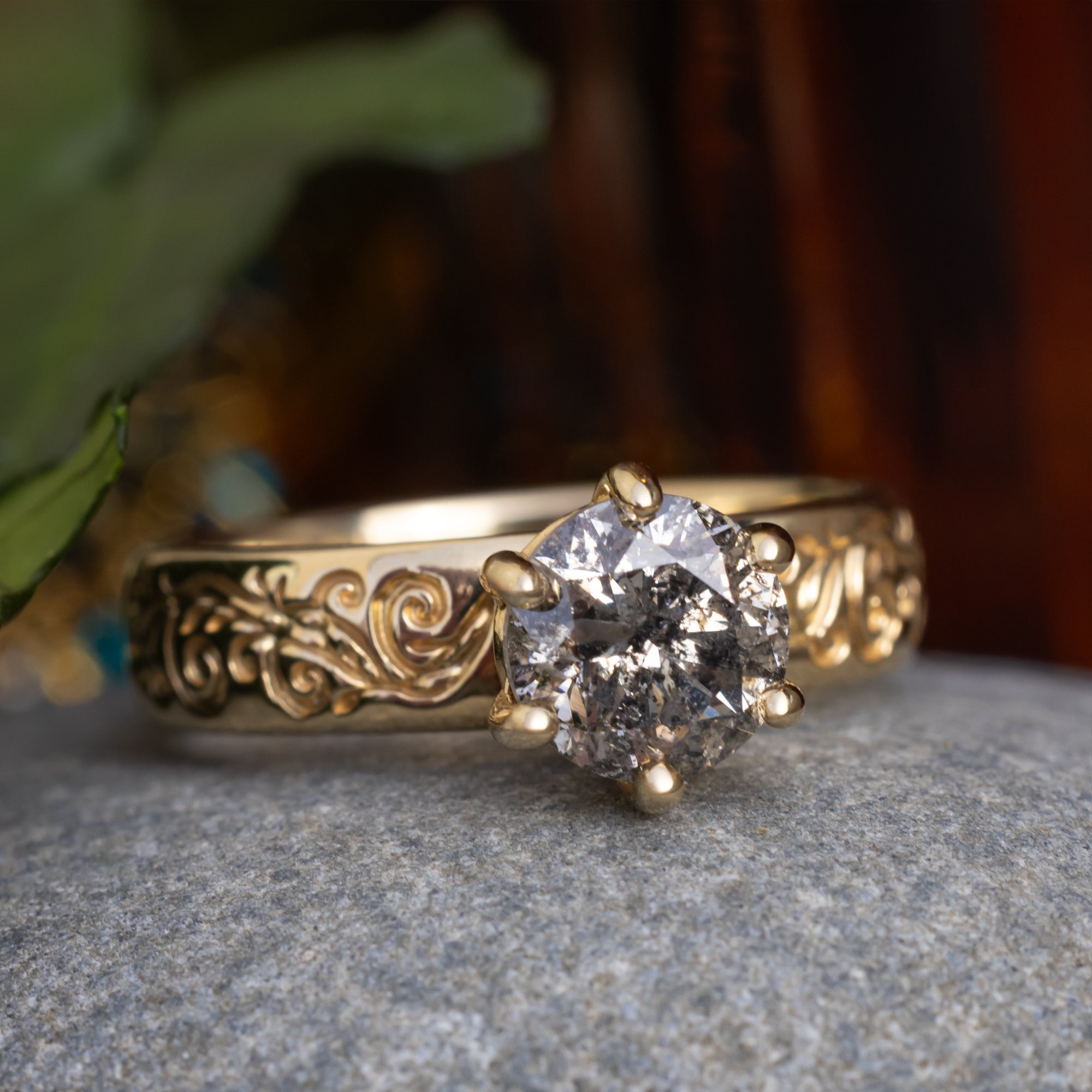 Gold ring with a salt & pepper diamond on a textured surface