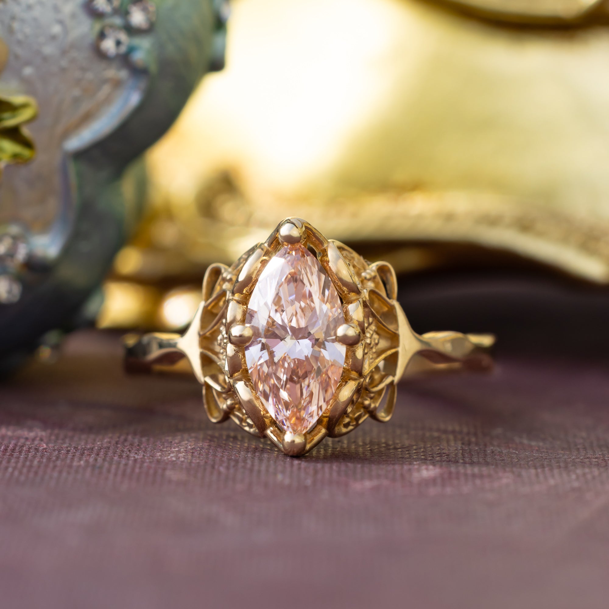 Gold ring with a pink lab diamond on a textured surface