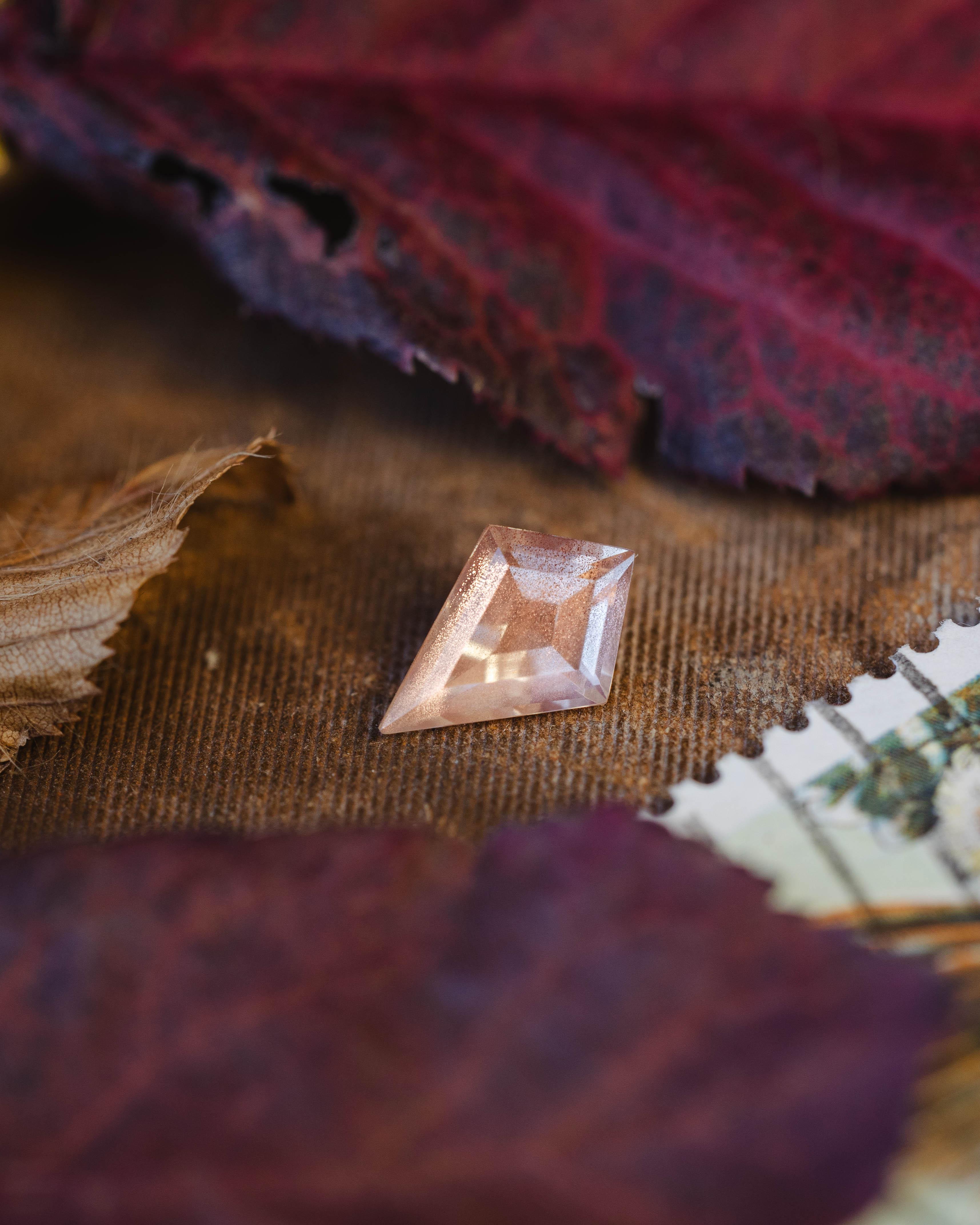 Kite cut sunstone on a textured fabric background with leaves