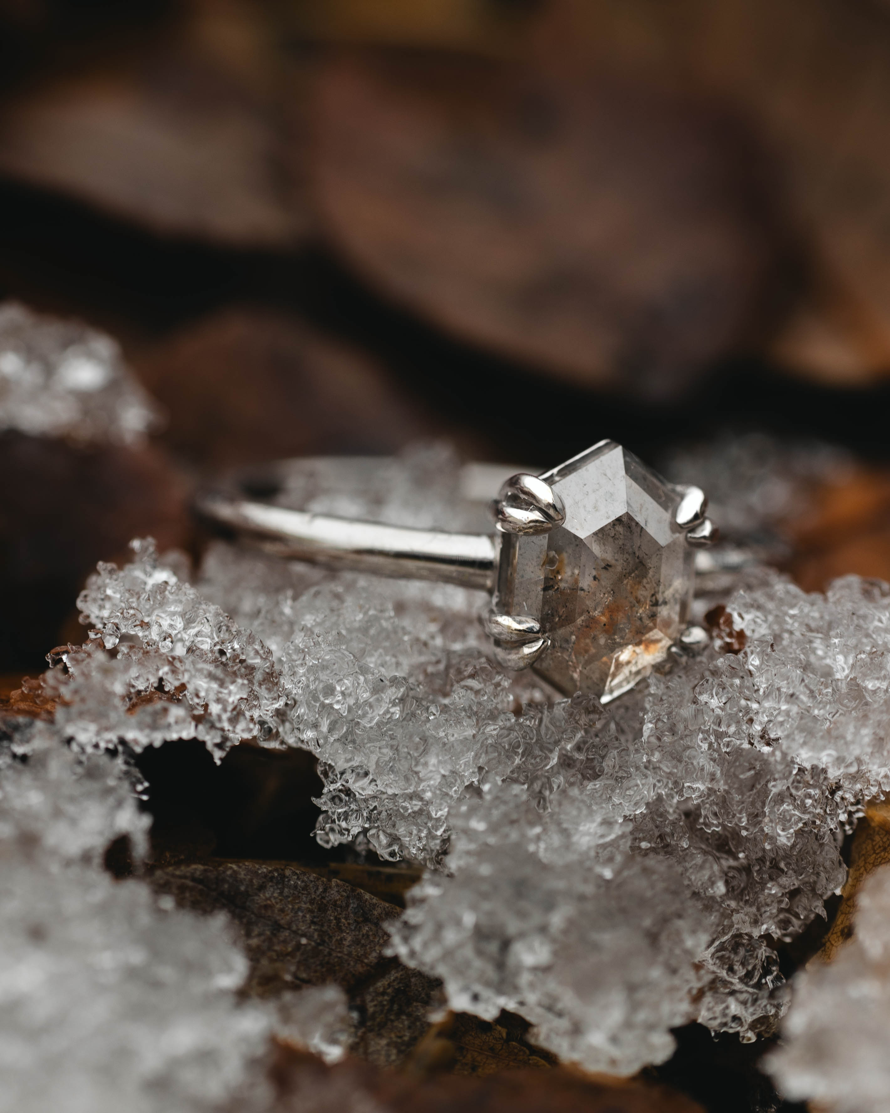 White gold ring with a hexagonal salt & pepper diamond on a snowy surface