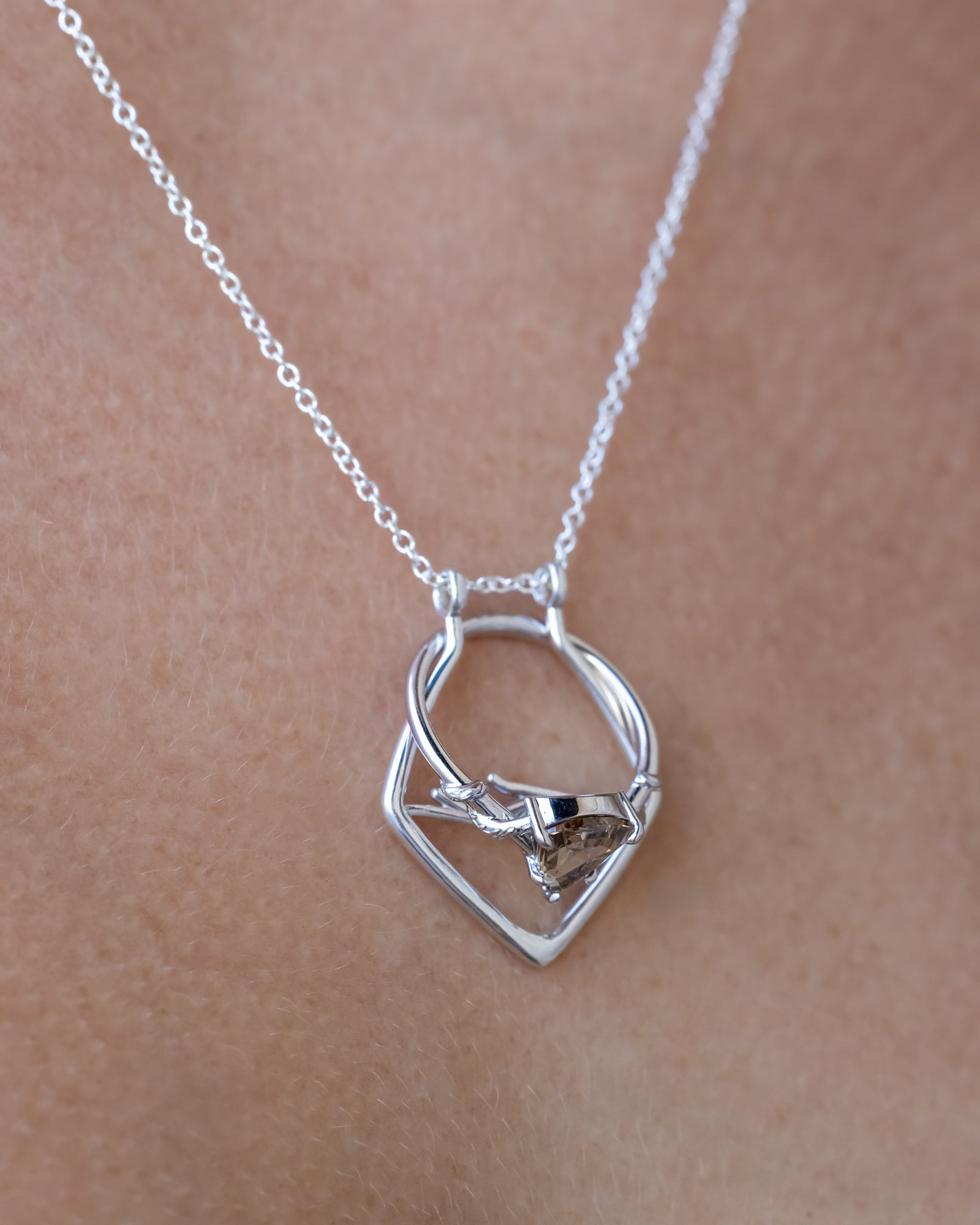 A silver necklace with an antler design on a model's neck
