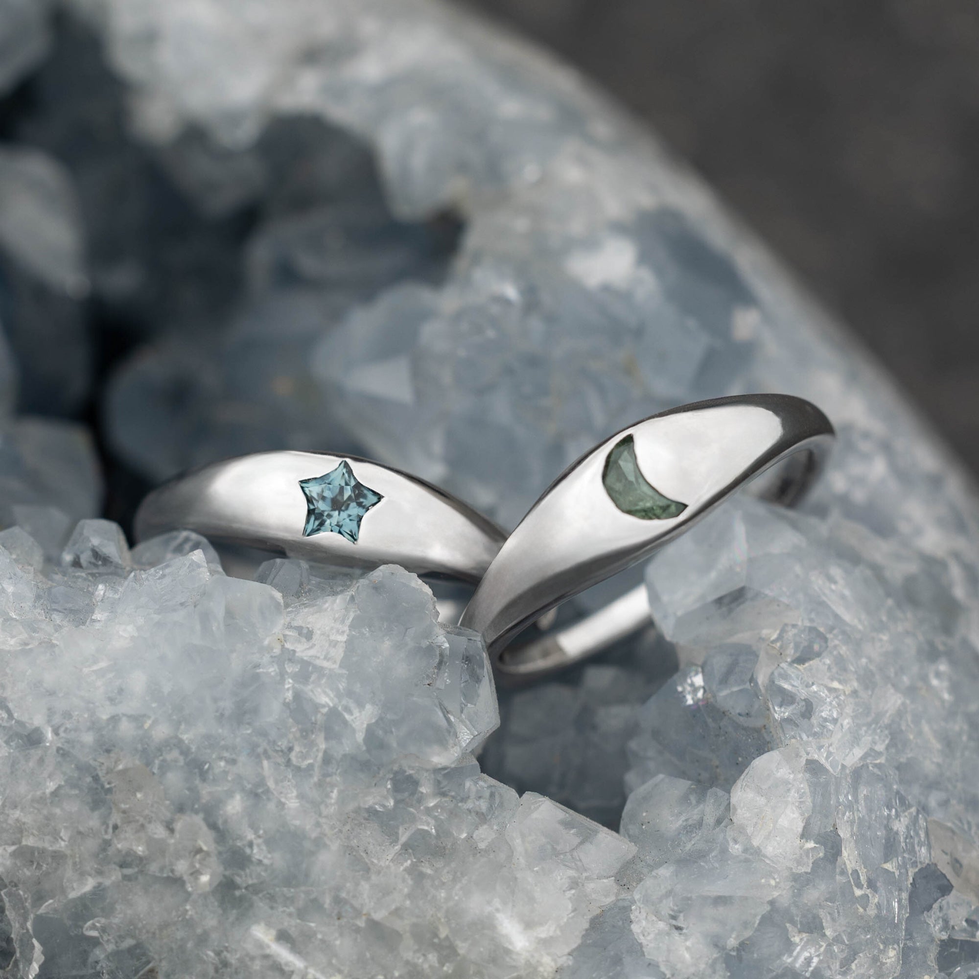 White gold ring with a green sapphire on a gray stone surface