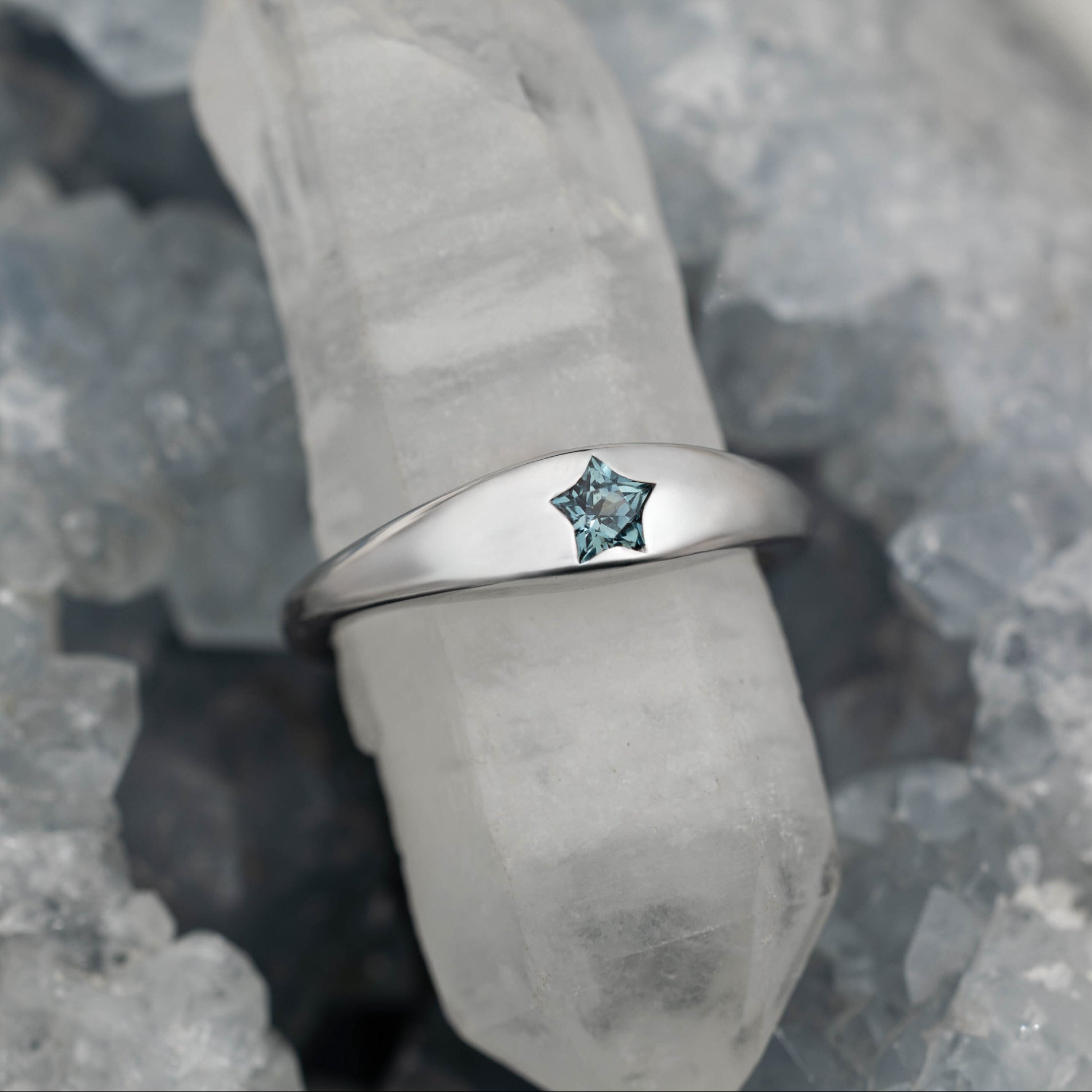 White gold ring with a green sapphire on a gray stone surface