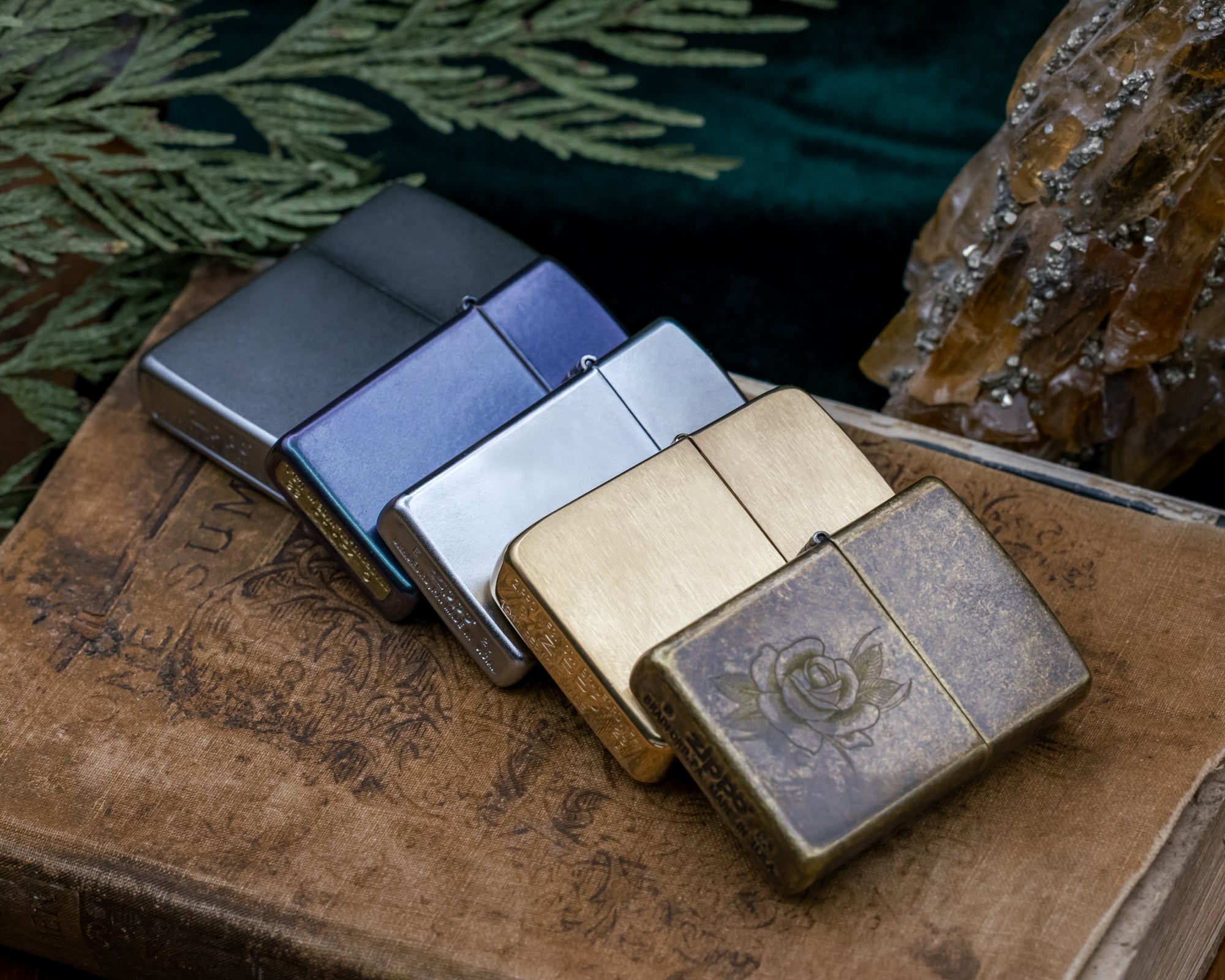 Four zippo lighters in different colors on a textured surface with a natural background