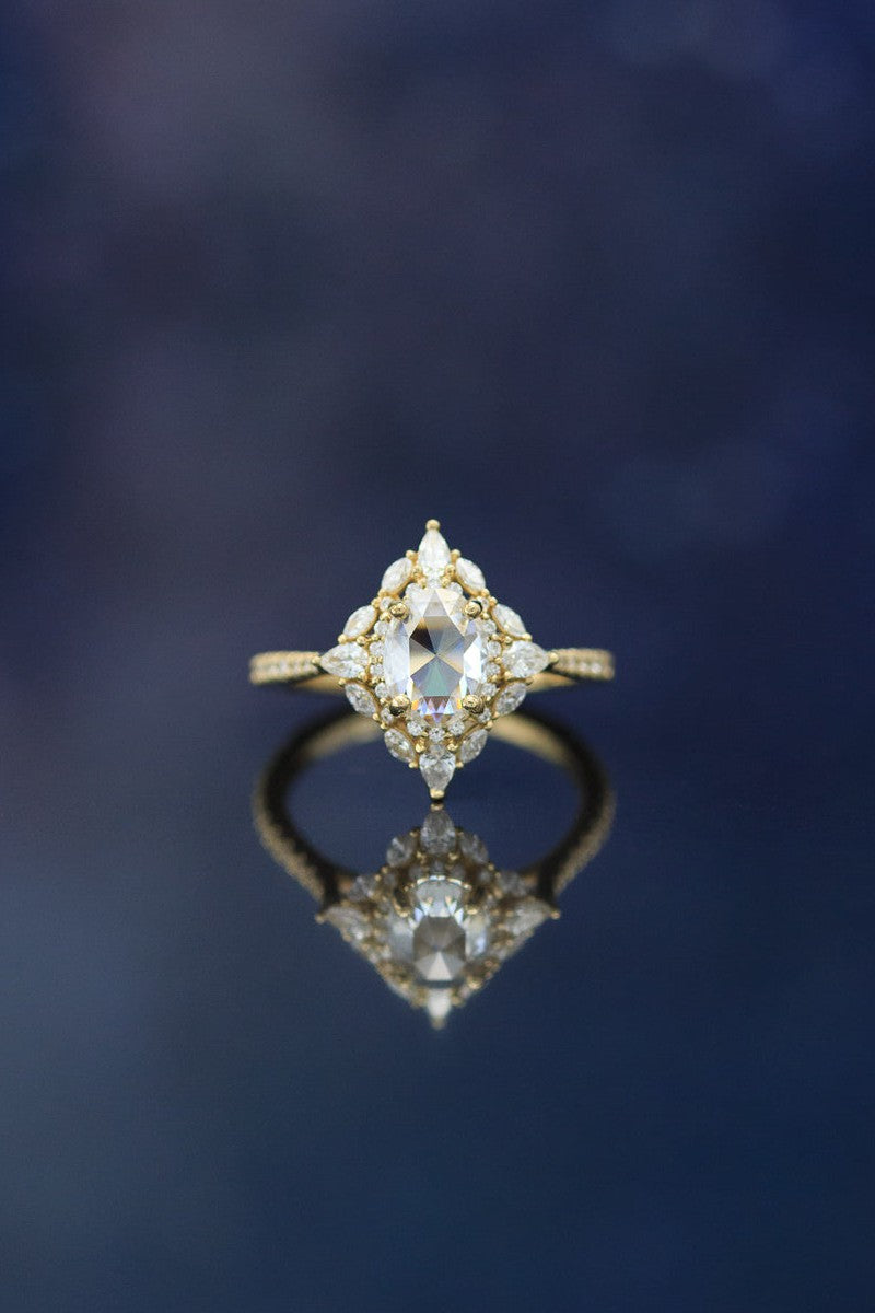 shown here is The "North Star", a halo-style oval moissanite women's engagement ring with delicate and ornate details and is available with many center stone options