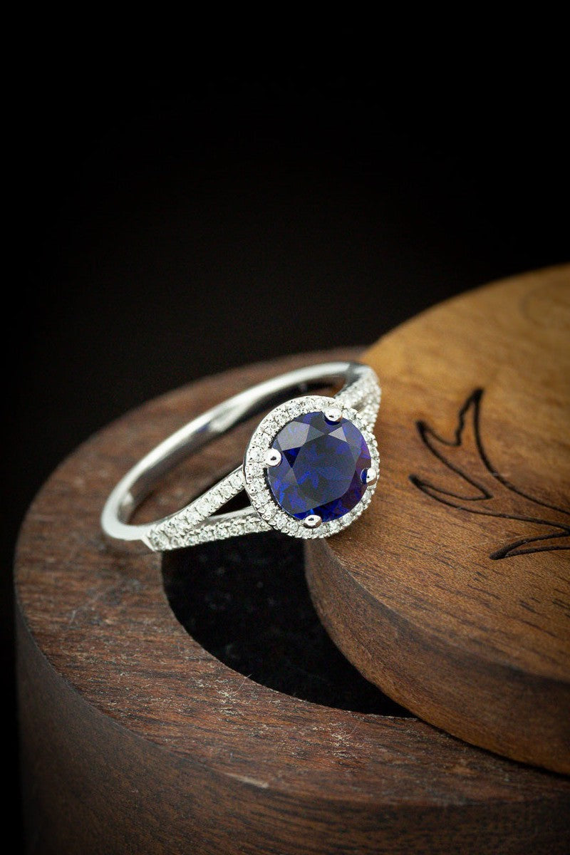  shown here is The "Aura", a birthstone ring with a split shank-style & lab-created blue sapphire women's ring with delicate and ornate details and is available with many center stone options