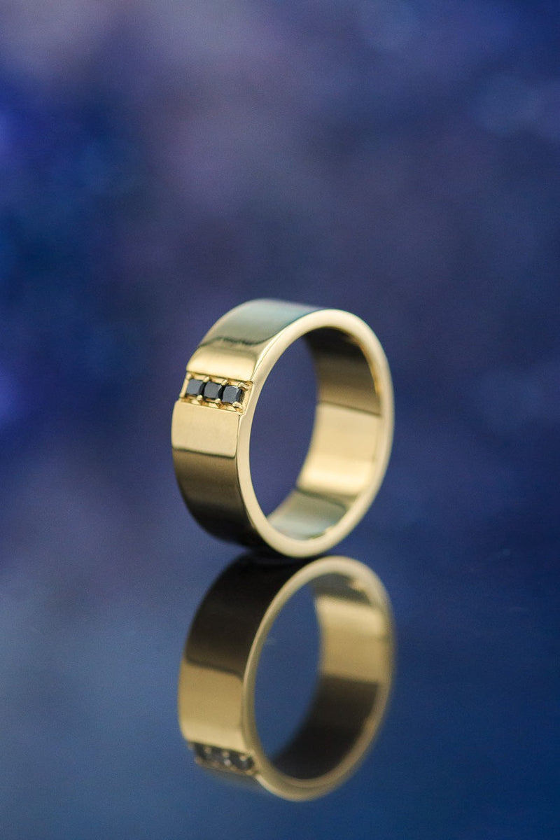 Shown here is  The "Orion", a custom, handcrafted men's wedding ring featuring a 14K gold band with 3 black diamonds which total 1/10 ctw. Additional inlay options are available upon request.
