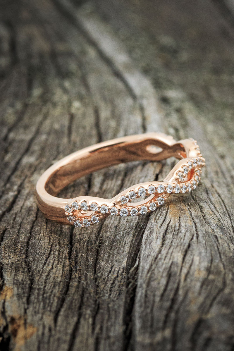 Shown here is a custom, handcrafted infinity-style women's stacking band featuring diamond accents, shown here on a 14K rose gold band.
