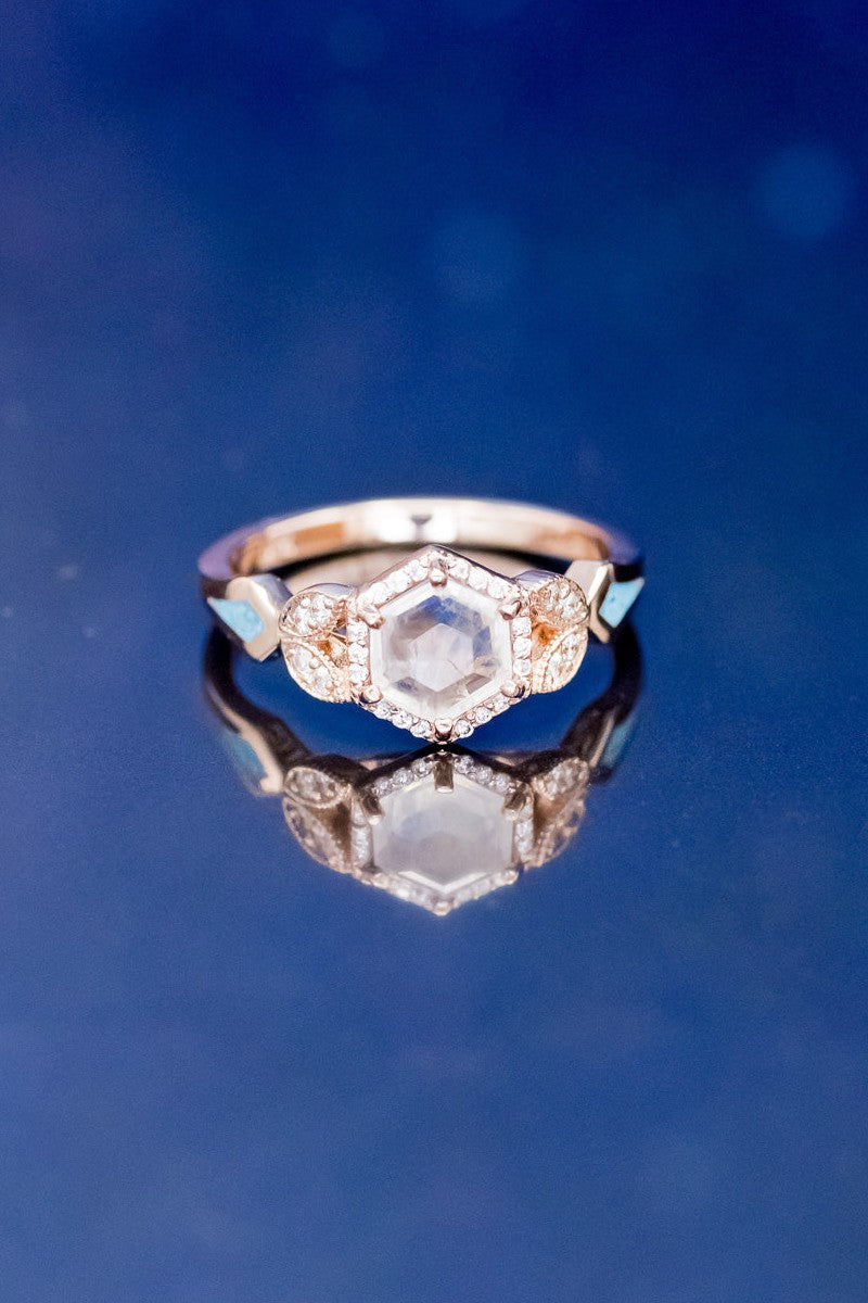 Shown here is The "Lucy in the Sky" petite, a halo-style faceted moonstone women's engagement ring with delicate and ornate details and is available with many center stone options, and is shown with turquoise inlays on both sides.