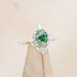 Shown here is The "North Star", an oval moss agate women's engagement ring with a diamond halo and accents.