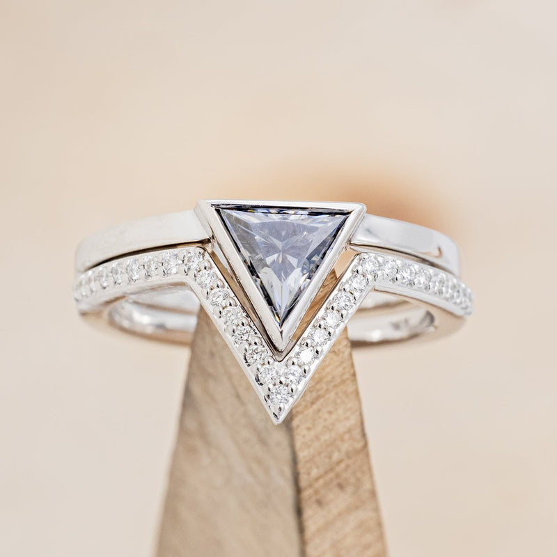 Shown here is  The "Jenny From The Block", a dainty-style triangle grey moissanite women's engagement ring with a diamond tracer. 