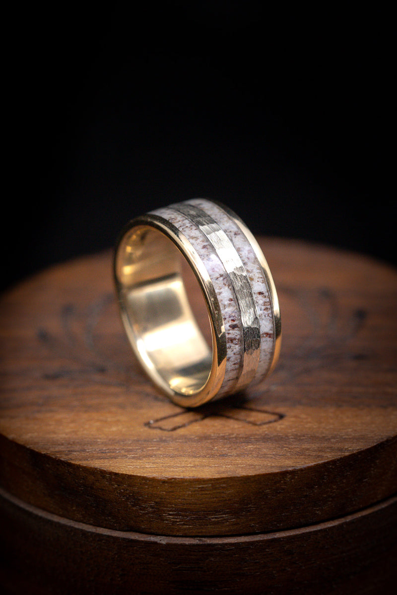 Shown here is  A custom, handcrafted men's wedding ring featuring a 14K yellow gold base with an elk antler inlay and a hammered 14K white gold inlay. Additional inlay options are available upon request.