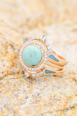 Shown here is The "Terra" bridal suite, a halo-style turquoise women's engagement ring with delicate and ornate details and is available with many center stone options. Shown here with two "Sama" tracers.