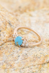 Shown here is The "Rhea", an accented-style turquoise women's engagement ring with delicate and ornate details and is available with many center stone options.