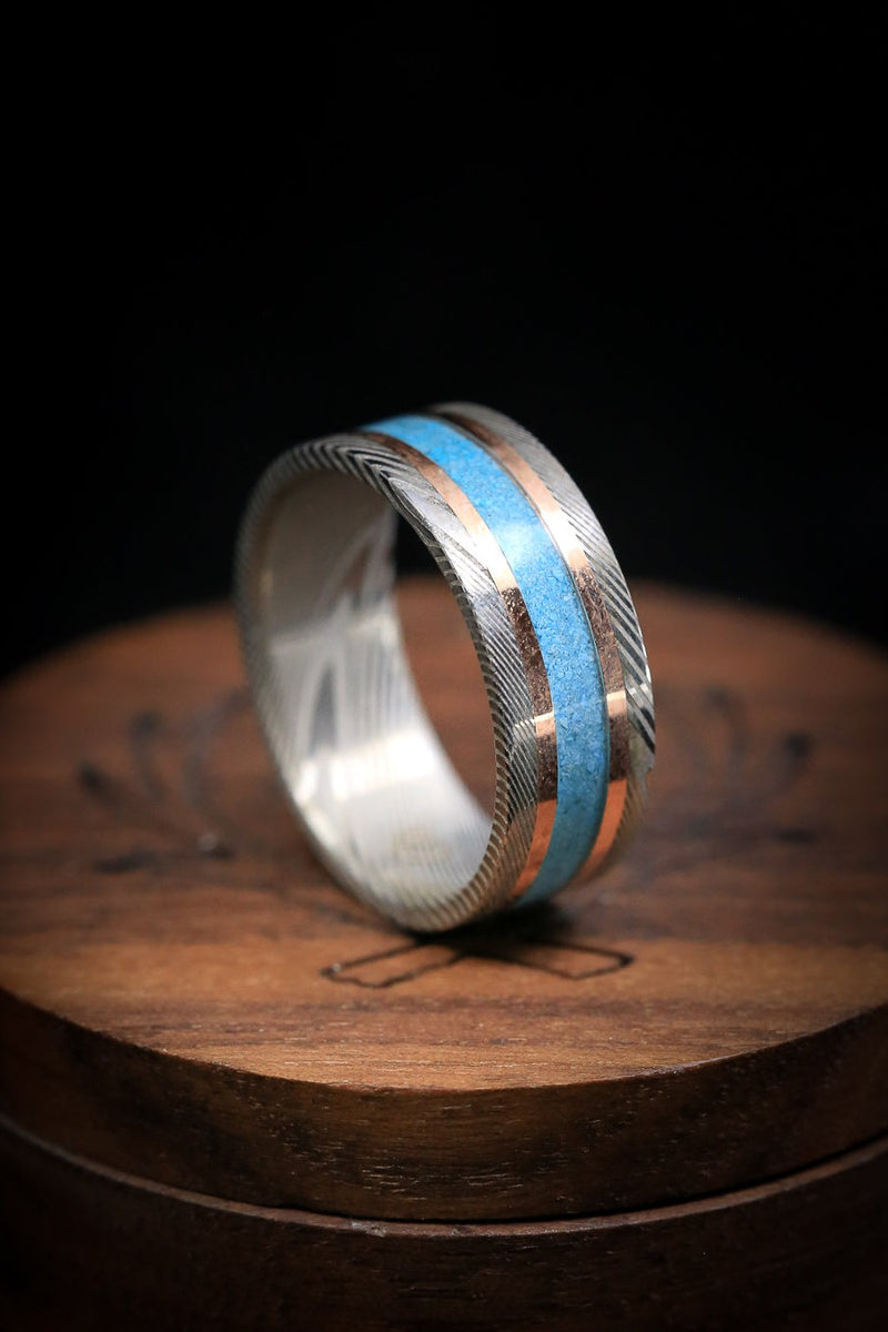 Shown here is a custom, handcrafted men's wedding ring featuring a thin turquoise inlay and two 14K rose gold inlays. Additional inlay options are available upon request.
