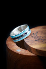 Shown here is a tilted angle of  "Rio", a custom, handcrafted men's wedding ring featuring a 14K white gold base with turquoise and patina copper inlays. The middle section also has 2 diamonds and 1 blue sapphire. Additional inlay options are available upon request.-Turquoise Wedding Ring with Blue Sapphire, Diamonds, and Patina Copper - Staghead Designs