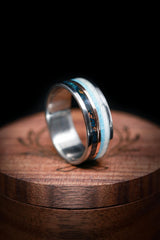 Shown here is A custom, handcrafted men's wedding ring featuring patina copper, a thin 14K rose gold inlay, turquoise, and antler inlays. Additional inlay options are available upon request.