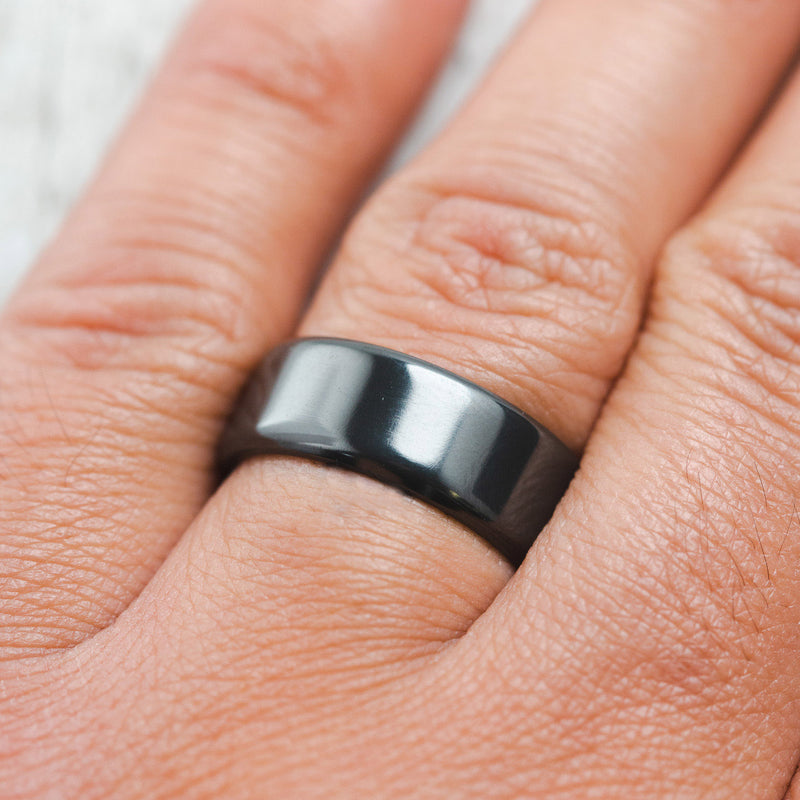Shown here a handcrafted men's wedding ring featuring a solid fire-treated black zirconium band, on hand, Additional inlay options are available upon request.