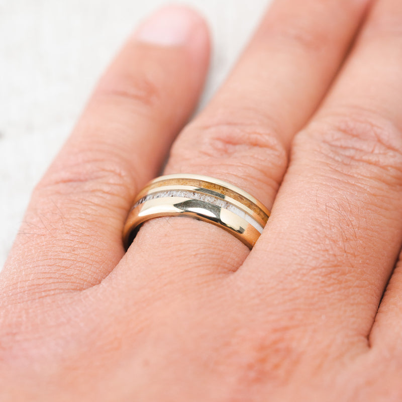 Shown here, Cosmo, a custom, handcrafted men's wedding ring featuring whiskey barrel oak and antler inlays, shown here on a yellow gold, on hand. Additional inlay options are available upon request.