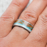 Shown here, The Expedition ,a custom, handcrafted men's wedding ring featuring a mountain engraving with whiskey barrel oak, antler and turquoise inlays, on hand. Additional inlay options are available upon request.