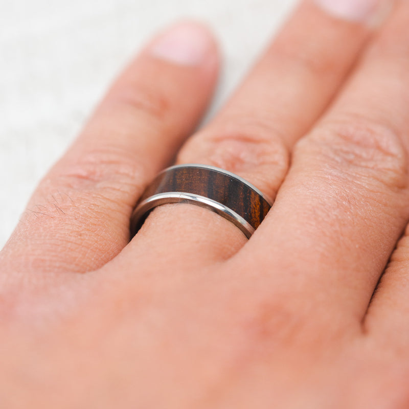 Shown here, Rainier, a custom, handcrafted men's wedding ring featuring an ironwood inlay, on hand. Additional inlay options are available upon request.