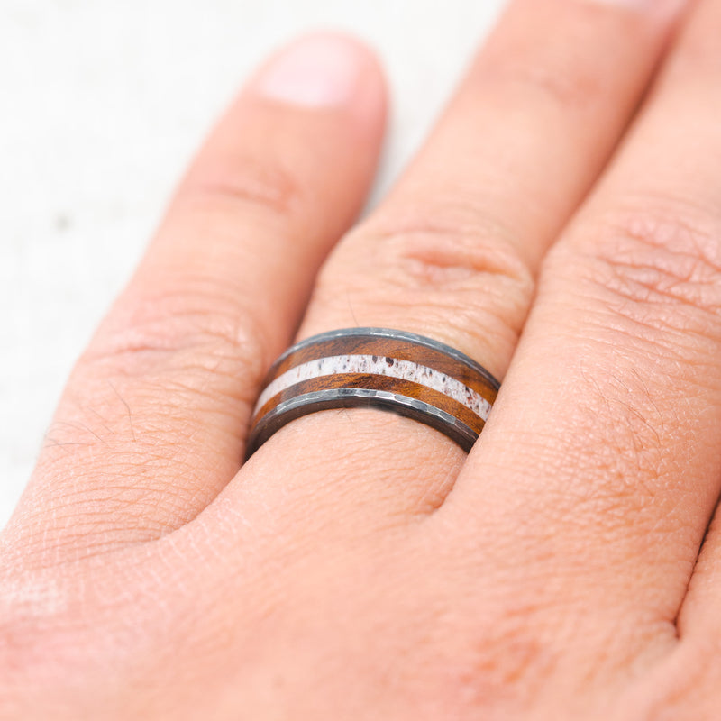 Shown here, Rainier, a custom, handcrafted men's wedding ring featuring an  ironwood and antler inlay on a hammered, fire-treated black zirconium band, on hand. Additional inlay options are available upon request.