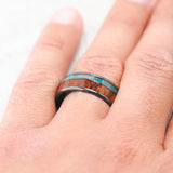 Shown here, Raptor, a custom, handcrafted men's wedding ring featuring a patina copper and redwood inlays, on hand.