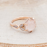 Shown here is "Lucy in the Sky" is a halo-style hexagon faceted rose quartz women's engagement ring with diamond accents, mother of pearl inlays, facing right. Many other center stone options are available upon request.