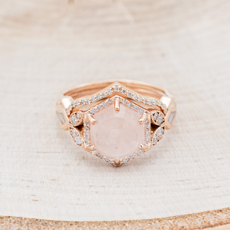  Shown here is "Lucy in the Sky" is a halo-style hexagon faceted rose quartz women's engagement ring with diamond accents, mother of pearl inlays, and a diamond tracer, facing front. Many other center stone options are available upon request. 
