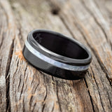 Shown here is "Vertigo", a handcrafted men's wedding ring featuring a mother of pearl inlay, tilted left.