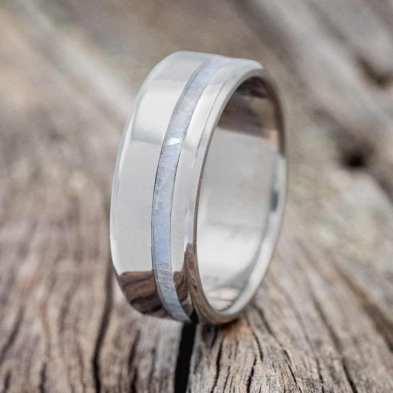 Shown here is "Vertigo", a custom, handcrafted men's wedding ring featuring a mother of pearl inlay, upright facing left. Additional inlay options are available upon request.