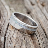Shown here is "Vertigo", a custom, handcrafted men's wedding ring featuring a mother of pearl inlay, tilted left. Additional inlay options are available upon request.