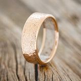 Shown here is a handcrafted men's wedding ring featuring a hammered finish and antler lining on any of our available base material options, upright facing left. Additional inlay options are available upon request.