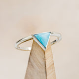 Shown here is "Jenny From The Block", a solitaire-style triangle turquoise women's engagement ring, on stand front facing. Many other center stone options are available upon request. 