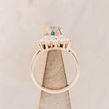 Shown here is "Esmeralda", a round cut spiny oyster turquoise women's engagement ring with diamond accents, side view on stand. Many other center stone options are available upon request.