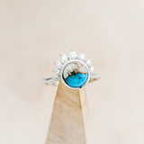 Shown here is "Esmeralda", a round cut spiny oyster turquoise women's engagement ring with diamond accents, on stand front facing. Many other center stone options are available upon request.